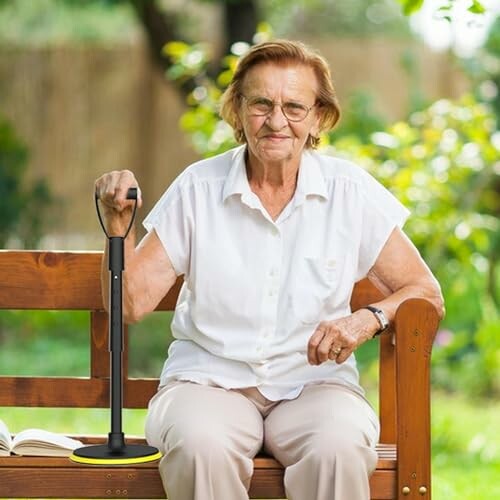 Ältere Frau sitzt auf einer Bank mit einem Gehstock.